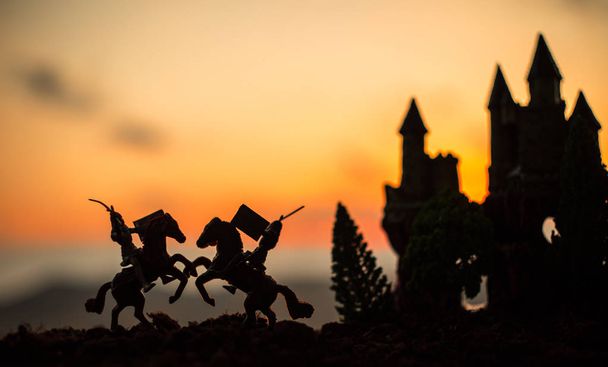 騎兵と歩兵の中世の戦闘シーン。個別のオブジェクトとして人物のシルエットは、古いゴシック様式城と夕日を背景に戦士の間戦います。選択と集中 - 写真・画像