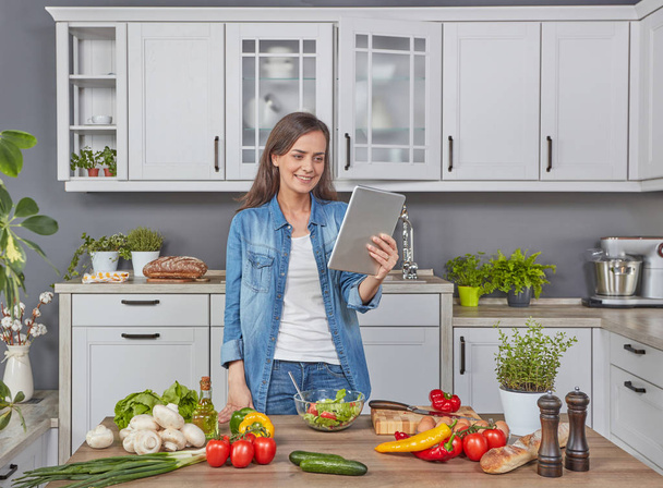 Woman with digital tablet cooking dinner - Fotoğraf, Görsel