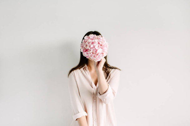 Молода жінка тримає рожевий букет з квітів гортензії на білому тлі. Концепція квіткової моди
. - Фото, зображення