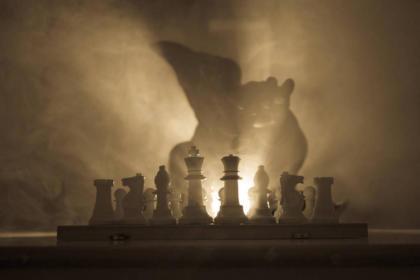 Un hombre jugando al ajedrez. Asustada silueta borrosa de una persona en el tablero de ajedrez con figuras de ajedrez. Fondo brumoso tonificado oscuro. Enfoque selectivo. Concepto de horror
 - Foto, imagen
