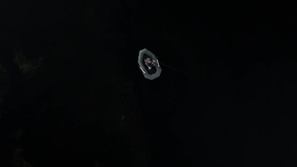 fisherman in a boat on a dark river, aerial view - Metraje, vídeo