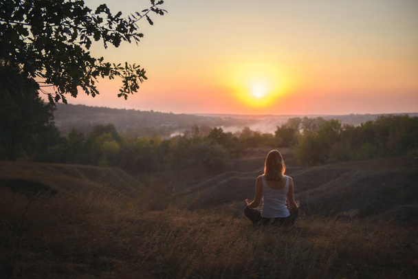 fiatal nő gyakorló jóga naplementekor  - Fotó, kép