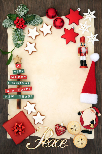 Uitnodiging voor het feest van Kerstmis of lege brief aan de Kerstman concept met vredesteken, decoraties, mince taart, gingerbread koekjes en winter flora op perkament op rustieke eiken achtergrond. - Foto, afbeelding