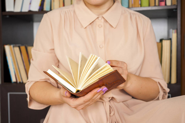 Молодая девушка в светлом платье выбирает книги в винтажной университетской библиотеке, читает книги и расслабляется
. - Фото, изображение