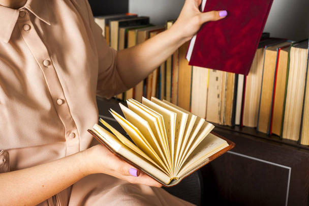 Young girl in a light dress is reading a book. Female hands hold a book in their hands - 写真・画像