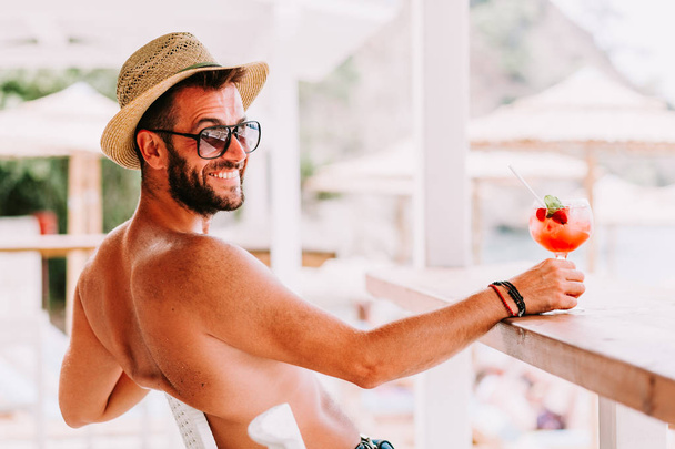 Giovane uomo che si gode un cocktail in un bar sulla spiaggia
 - Foto, immagini