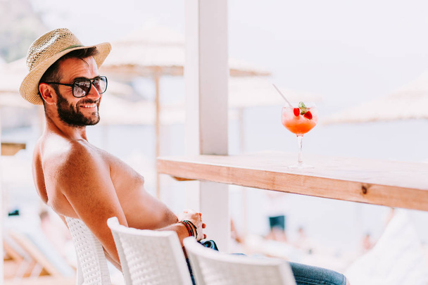 Young man enjoying cocktail in a beach bar - Foto, Imagem