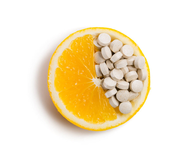 Tabletit, joissa on vitamiineja appelsiiniviipaleessa. Eristetty valkoisella pohjalla
. - Valokuva, kuva