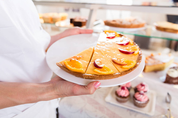 Baker femme de vente mettant tartes et gâteaux sur l'affichage
 - Photo, image