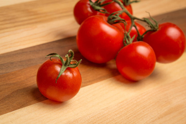 Tomates cherry con tallos en tabla de cortar de madera
 - Foto, imagen