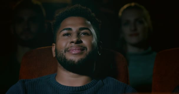 Een jonge man aanbrengen in een movie theater glimlachen, genieten van lettend op een film - Video