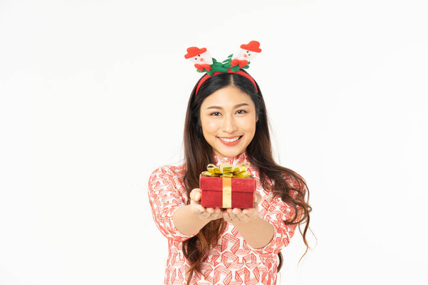 Photo of asian curious woman in red dress rejoicing her birthday or new year gift box. Young woman holding gift  box with red bow being excited and surprised  holiday present isolated white background - Foto, Imagem