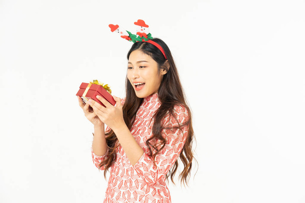 Photo of asian curious woman in red dress rejoicing her birthday or new year gift box. Young woman holding gift  box with red bow being excited and surprised  holiday present isolated white background - Fotoğraf, Görsel