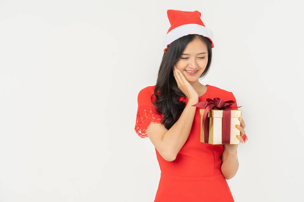 Photo of asian curious woman in red dress rejoicing her birthday or new year gift box. Young woman holding gift  box with red bow being excited and surprised  holiday present isolated white background - Valokuva, kuva