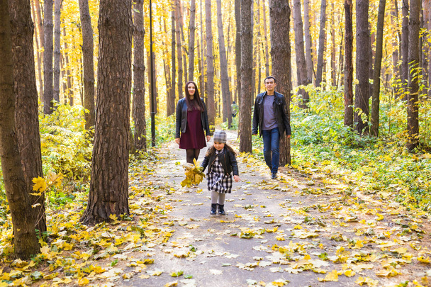 Lidi, rodinu a volný čas koncept - Smíšené rasy otec a matka se bavit v podzimním parku s jejich dcerou - Fotografie, Obrázek