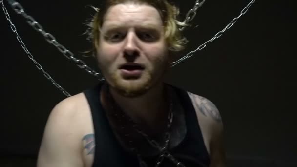 Przerażony więzień blond próbuje zerwać łańcuchy - Materiał filmowy, wideo