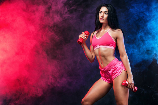 Attractive young fitness woman athlete and bodybuilder holding dumbbell . Copy space for fitness nutrition ads. - Fotografie, Obrázek