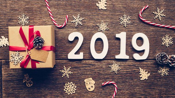 Bovenaanzicht houten cijfers vormen het nummer 2019, voor het nieuwe jaar 2019 op rustieke houten geschenkdoos rood lint en Kerstdecoratie. - Foto, afbeelding