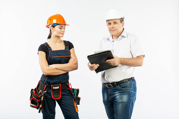 empreiteiros que discutem o plano de construção sobre fundo branco. Foreman com mulher construtor usando capacetes
. - Foto, Imagem