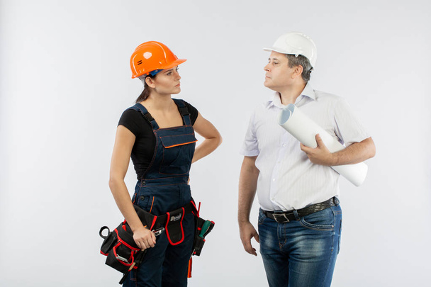 empreiteiros que discutem o plano de construção sobre fundo branco. Foreman com mulher construtor usando capacetes
. - Foto, Imagem