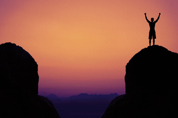 Sziluettjét éljenzés ember hegyekben, mint szimbólum a siker a sunset - Fotó, kép