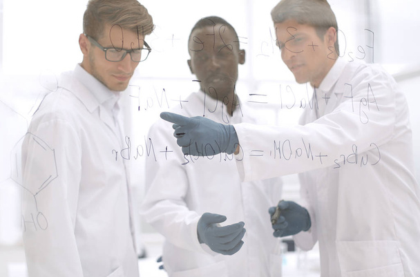 Молодой ученый показывает палец на стеклянной доске
 - Фото, изображение