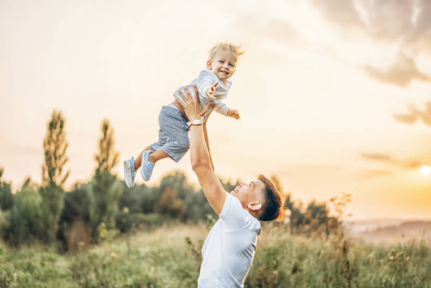 Padre sosteniendo pequeño hijo en sus brazos al aire libre
 - Foto, imagen