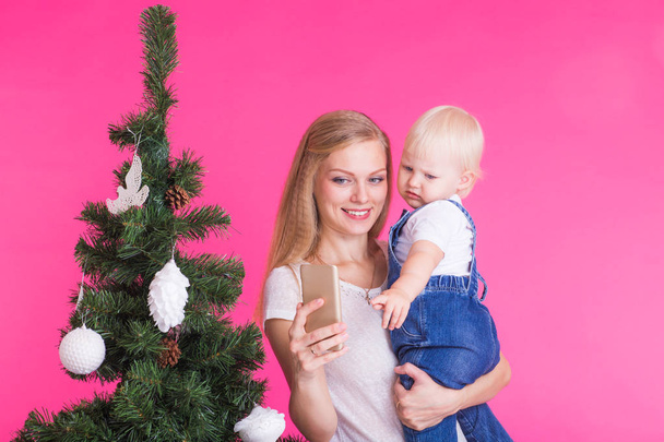 Mother and little daughter taking a selfie near Christmas tree - Photo, Image