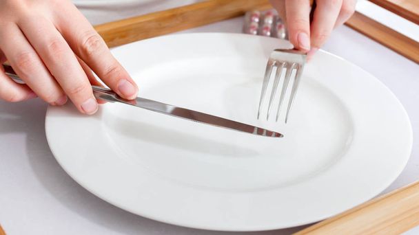 空の皿の上でフォークとナイフを保持している女性の手のクローズ アップ画像 - 写真・画像