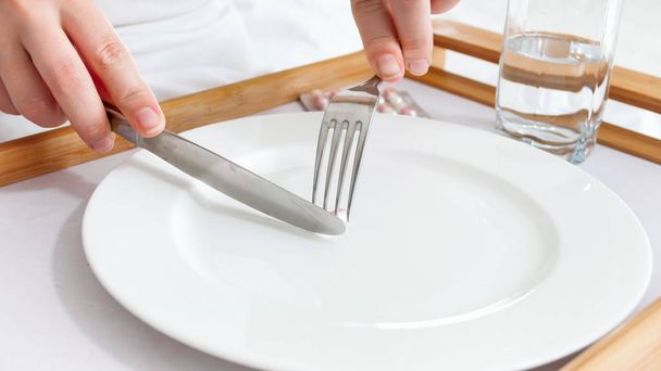 Close-up foto van zieke vrouw vork en mes te houden en het eten van pillen - Foto, afbeelding