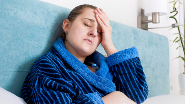 Retrato de close-up de mulher doente pegou frio deitado na cama e sofrendo de dor de cabeça
 - Foto, Imagem