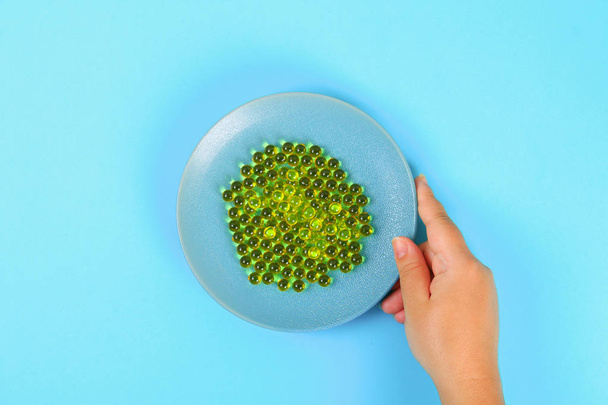 Plate with capsules of fish oil on a blue table background. Top view, copy space, flat lay - Fotoğraf, Görsel