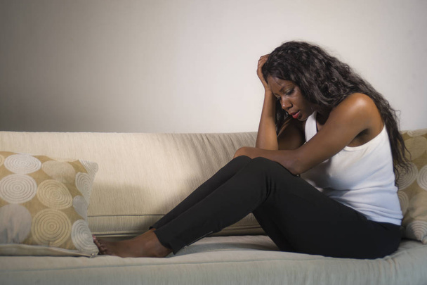young attractive and sad black African American woman sitting depressed at home sofa couch feeling anxious and frustrated suffering depression problem and anxiety crisis or period pain - Foto, immagini