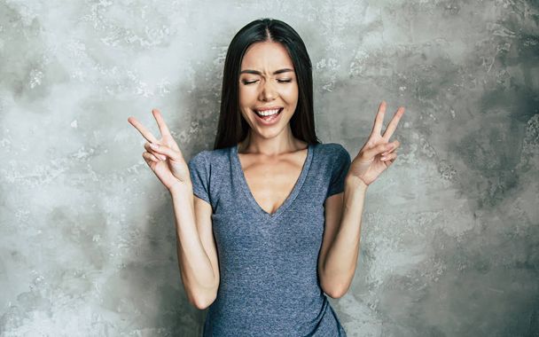 Cheerful young woman showing peace signs - Фото, изображение