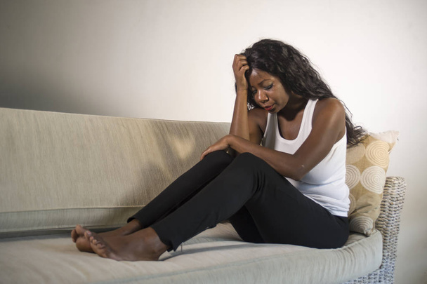 young attractive and sad black African American woman sitting depressed at home sofa couch feeling anxious and frustrated suffering depression problem and anxiety crisis or terrible headache - Foto, immagini