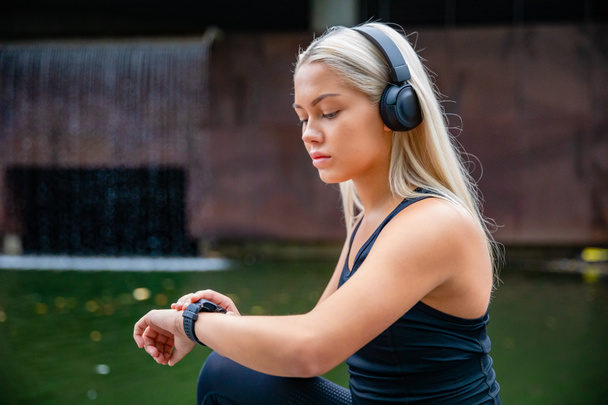 Σπορ αθλήτρια ακούγοντας μουσική στα ακουστικά ενώ χρησιμοποιώντας S - Φωτογραφία, εικόνα