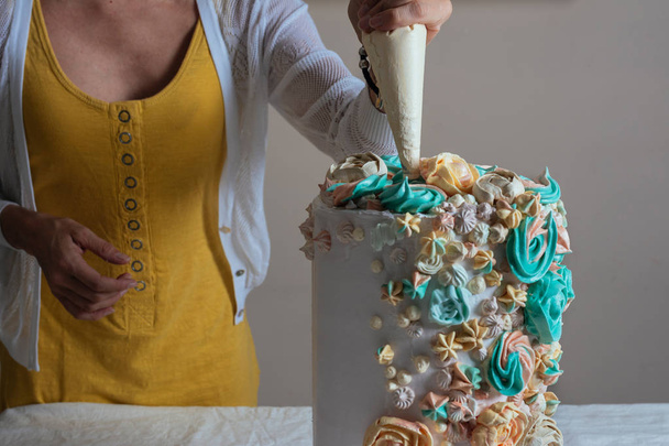 Femme pâtissier décorant un gâteau avec un sac à pâtisserie à la crème
 - Photo, image