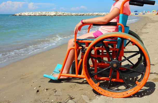 malá holka na vozíku s speciálních kovových kol jít na pláži u moře - Fotografie, Obrázek