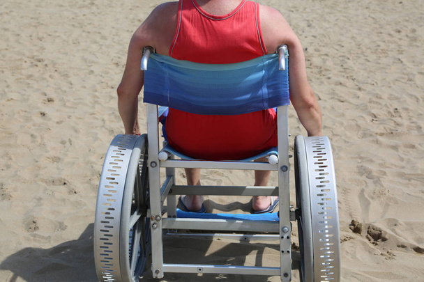 Erwachsene im speziellen Rollstuhl am Strand im Sommer - Foto, Bild