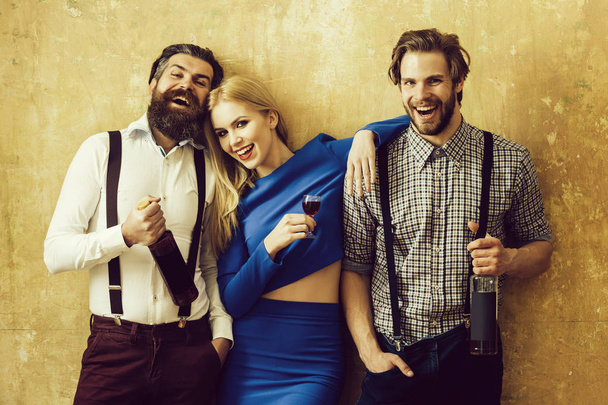 Men holding wine bottles and girl with glass of liqueur - Foto, Bild