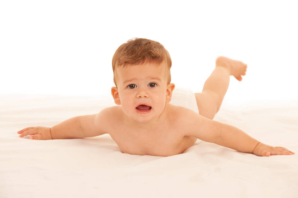Hapy baby boy in playing on bed isolated over white - 写真・画像