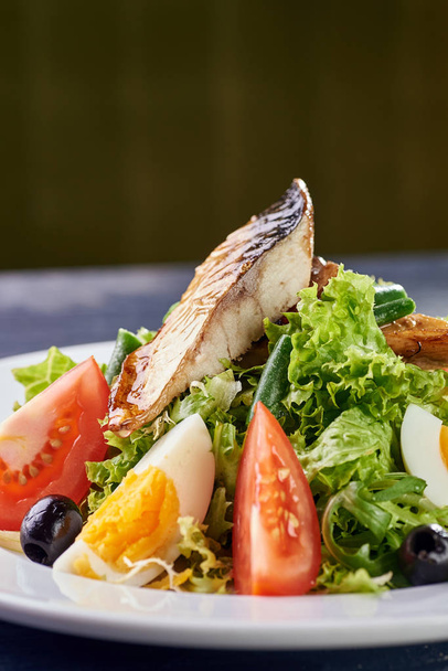 Een moderne variant van Caesar salade. Vissalade met eieren en groenten. Een stuk vlees en vis wordt gegrild naar een smaakvolle korst. Verse, sappige komkommers, tomaten, sla, Groenen en asperges. - Foto, afbeelding