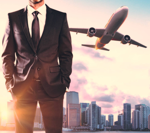 Вид спереди неузнаваемого бизнесмена с летающим самолетом на фоне города. Мыслить и путешествовать
 - Фото, изображение