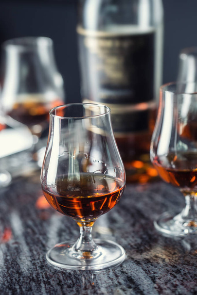 Cups with a cognac rum brandy or whiskey drink on a bar counter in night club. - Фото, зображення