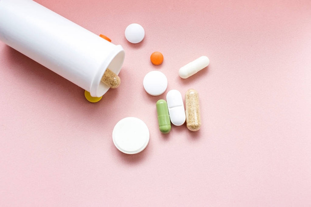 Diverse pillole farmaci o compresse che fuoriescono da una bottiglia di plastica bianca aspirina o antibiotici paracetamolo
 - Foto, immagini