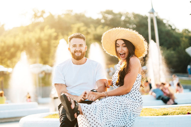 Handsome bearded man and his beautiful girl resting near fountains - Photo, Image