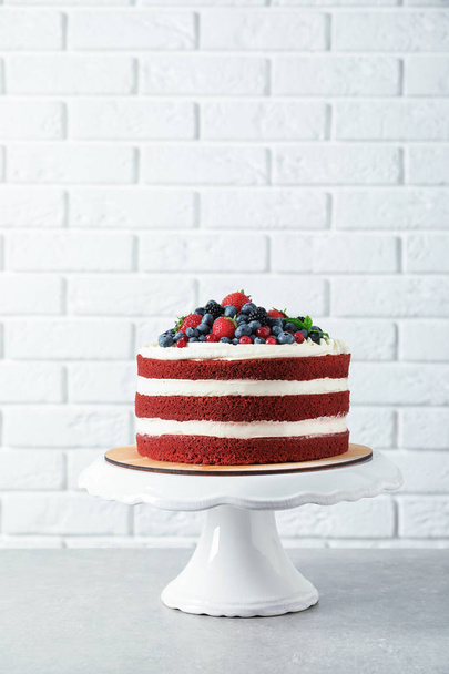 Stand with delicious homemade red velvet cake near brick wall - Foto, Imagen