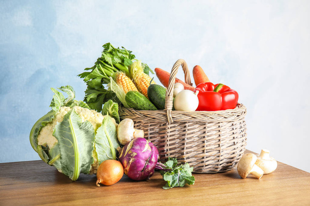 Basket full of fresh healthy vegetables on table against color background - Photo, Image