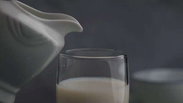 Pouring milk from a pitcher in a glass - Footage, Video
