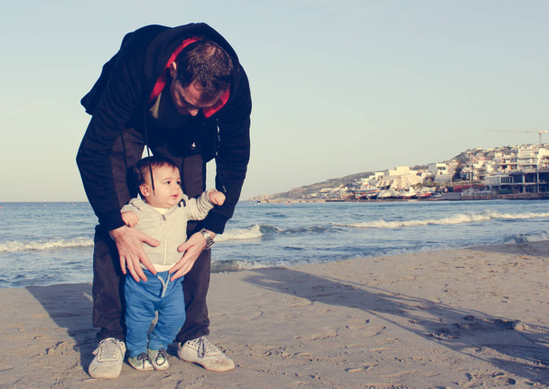 Apu és a baba fiú, a homokos strand ősszel, arc-Kifejez boldog család - Fotó, kép